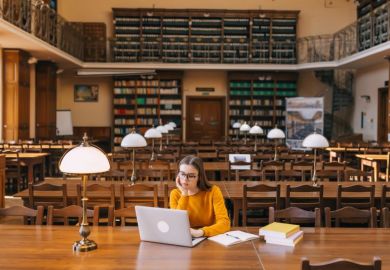 Student studying on laptop in library
