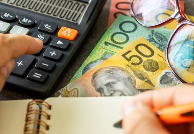  Australian dollars together with a calculator, hand writing down the results in a notebook