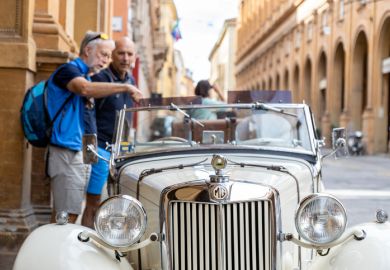 Two men admiring an MG T-Series car parked in the city centre in Bologna