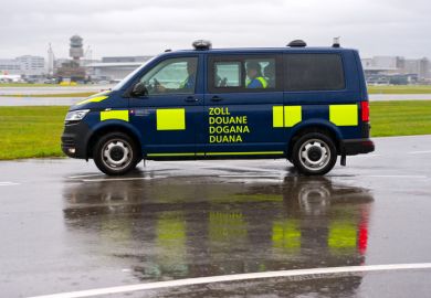 Dark blue van of Swiss customs passing at Zürich Kloten Airport on a rainy autumn day.