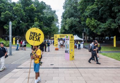 Volunteer student holding a sign offering assistance to visitors on University of New South Wales (UNSW) Orientation Week (O Week)