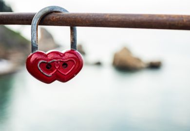Red double heart padlock hangs on bridge