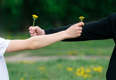 Two people exchanging dandelion flowers outdoors