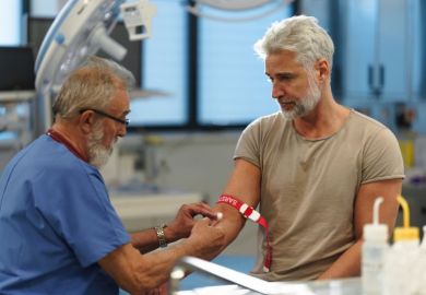 Older doctor drawing blood from patient's arm