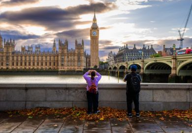 Rear view of a tourist couple taking photos of Big Ben and the Houses of Parliament from the south side of Westminster Bridge on the Thames embankment. Rear view of a tourist couple taking photos of Big Ben and the Houses of Parliament from the south side of Westminster Bridge on the Thames embankment.