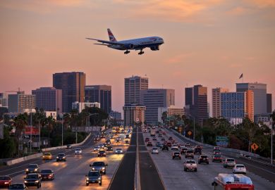  British Airways Boeing 777 flying over crowded freeway to land at Lindberg Field San Diego International Airport.