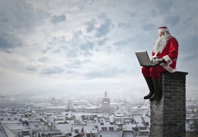 Santa sitting on a chimney with a laptop
