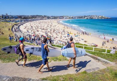 Three surfers heading to the Bondi Beach Bondi beach with their surf boards on a sunny day.