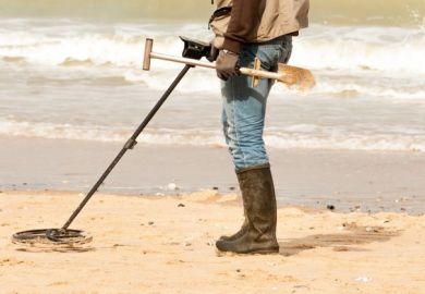 Person on beach using metal detector
