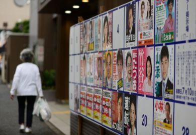 Woman walks past election posters Woman walks past election posters