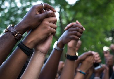 BAME academics are facing dual pandemics of Covid and racism. Interlocked hands at a Black Lives Matter protest. BAME academics are facing dual pandemics of Covid and racism.