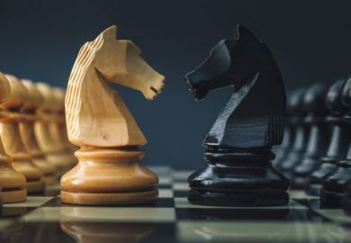 A black and white pair of chess knights face each other
