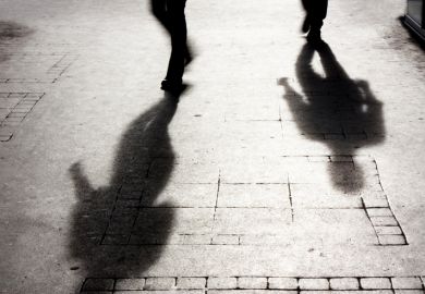 Shadow of two people on pattered sidewalk in black and white