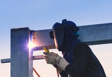 Worker welding parts of steel construction together