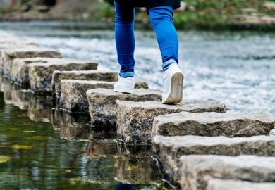 Woman crossing stepping stones on a river