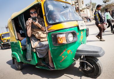 The smiling girl with camera on a tuk-tuk.