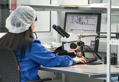 Control operator checks finished circuit board in plant for production of electronic equipment.