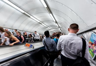 Men riding escalator walking down standing in underground tube