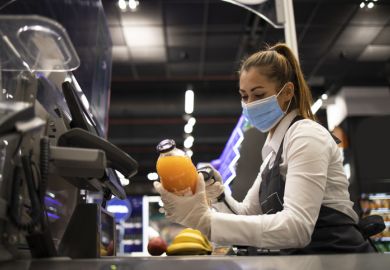 A checkout worker wearing a mask A checkout worker wearing a mask