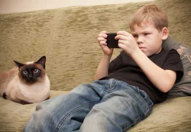 Boy playing Candy Crush on sofa