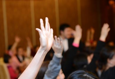 Students putting hands up in lecture theatre
