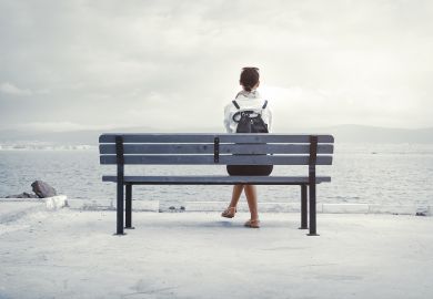 Woman sits alone on a bench Woman sits alone on a bench illustrating the isolating experience of transitioning from academia into industry