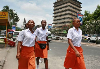 Girls walk along a street in Dar es Salaam, Tanzania