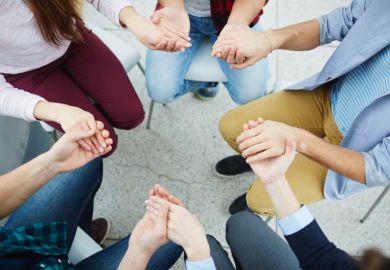 People holding hands, sitting in a circle