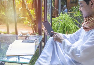 A Pakistani man works on a phone in a coffee shop