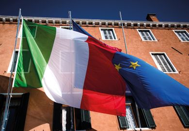 Italian flag flying in front of European Union flag, to suggest how Italy’s discrimination against foreign lecturers defies European law and justice