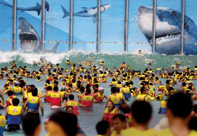 Swimmers in identical life preservers in the sea, face up to giant sharks gnashing at a metal grille