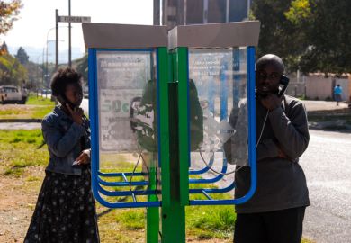 Johannesburg , Gauteng  South Africa -august 31 2012  man and woman talking on a sidewalk pay phone midday Rosettenville Johannesburg