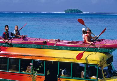 people sitting in kayaks on top of a bus