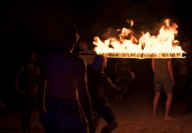 Koh Tao, Thailand - December 10, 2017 Young people partying and dancing limbo at fire show on the beach