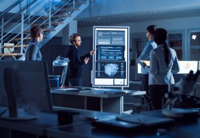 People in a lab meeting look at screens