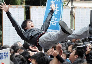 Laughing student being thrown in air by friends