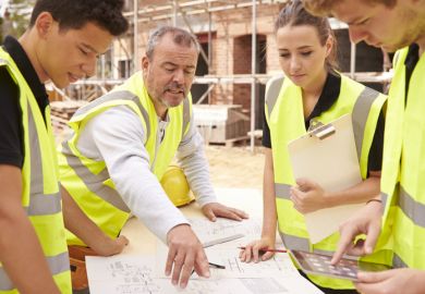 Young builders study blueprint on a building site, illustrating workplace learning