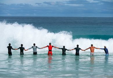 A line of people holding hands facing a wave