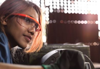 An Asian woman works heavy machinery