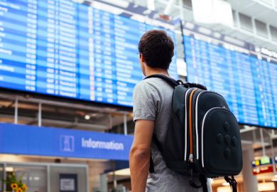 Male student looking at airport departures board Male student looking at airport departures board