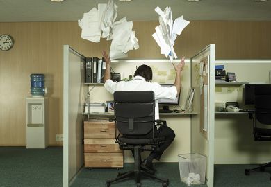 Man at desk throwing papers in the air