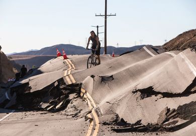 Man cycles along severely damaged road