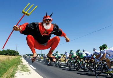 Man dressed as devil jumping beside Tour de France cycling race Man dressed as devil jumping beside Tour de France cycling race