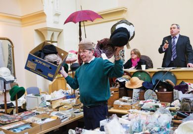 Man holding collection of hats at auction