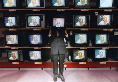 Man holding television in front of face in television shop