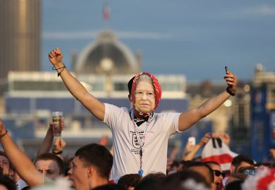 Man in crowd in England football shirt with Queen mask