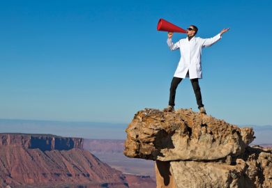 Man in lab coat shouting from rock with megaphone