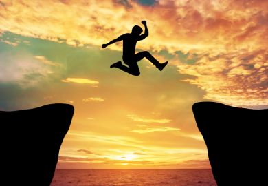 Man jumping between rocks against sunset
