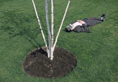 Man lying on the gras covering his face with a book