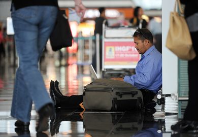A man uses his laptop while waiting at Hong Kong's international airport, illustrating that many PhD applicants have been left in limbo after a computer glitch affected their application for an Australian visa.